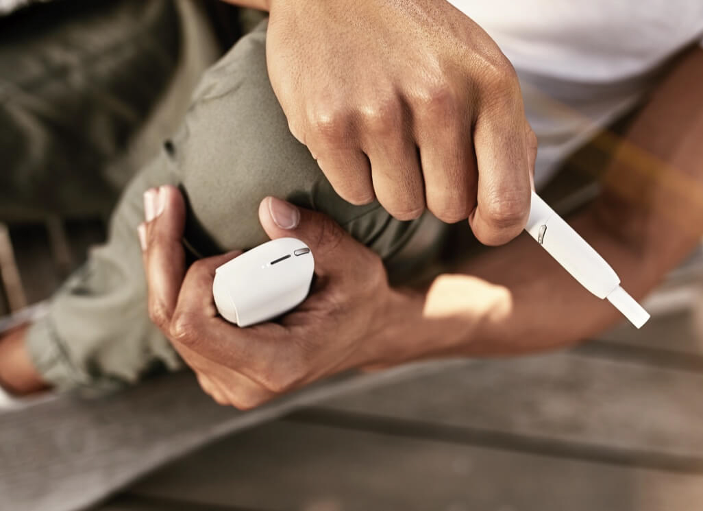 Hænder holder IQOS 3 DUO set oppefra