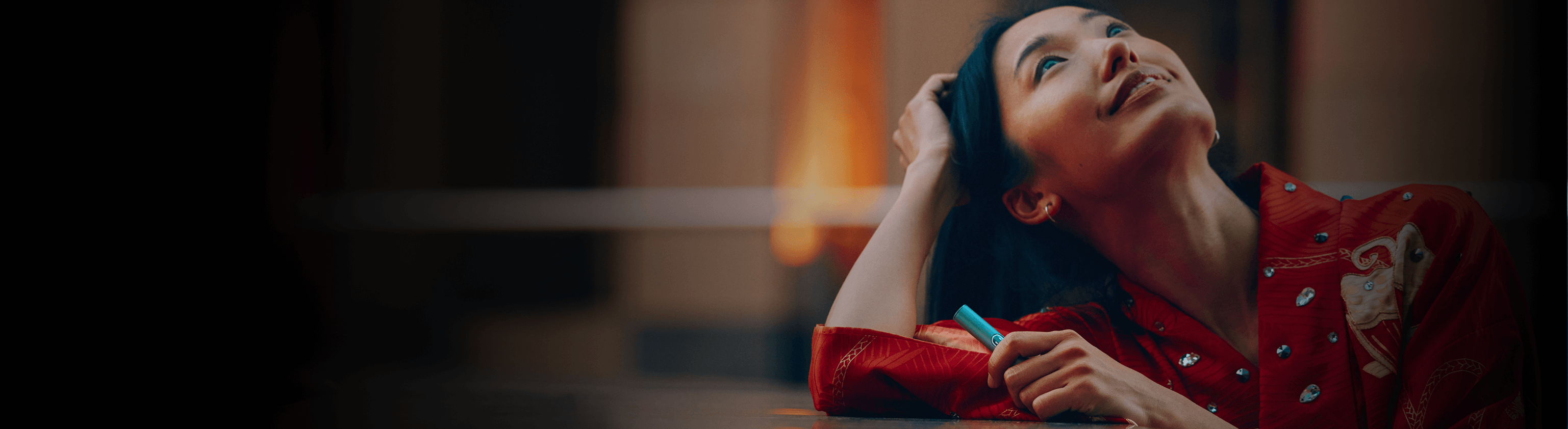 A woman holding an iqos iluma i holder looking up