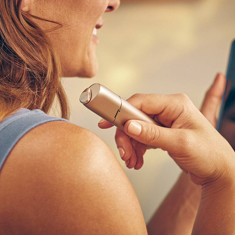 A woman showing off her IQOS device