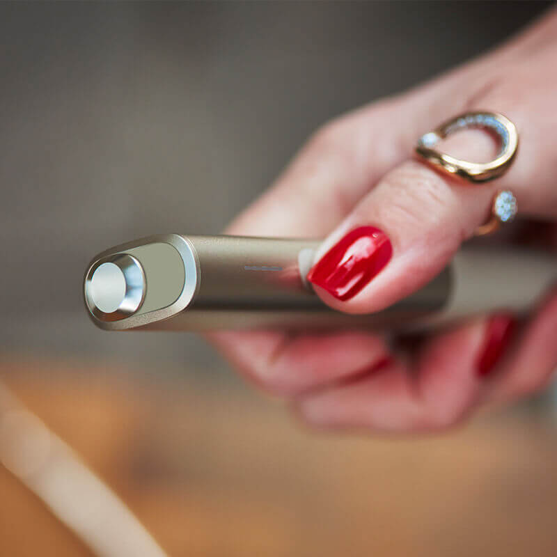 A woman with red nails holding her IQOS device