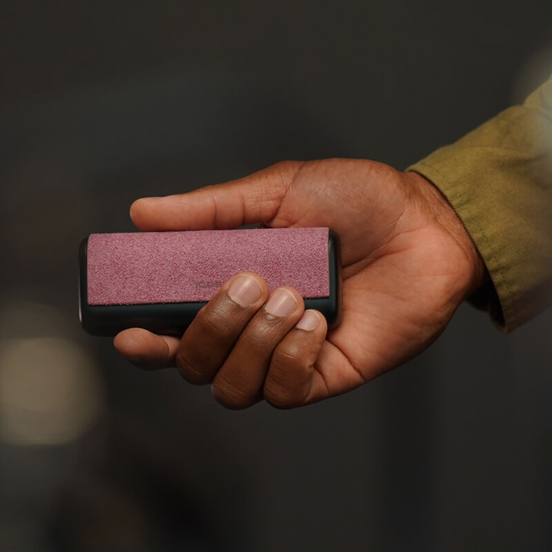 A person holding an IQOS ILUMA Pocket Charger and Holder. 