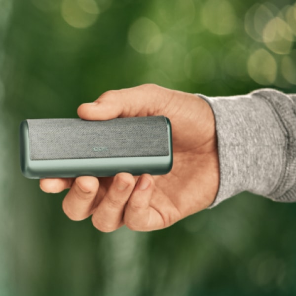 A person holding an IQOS ILUMA Pocket Charger and Holder. 